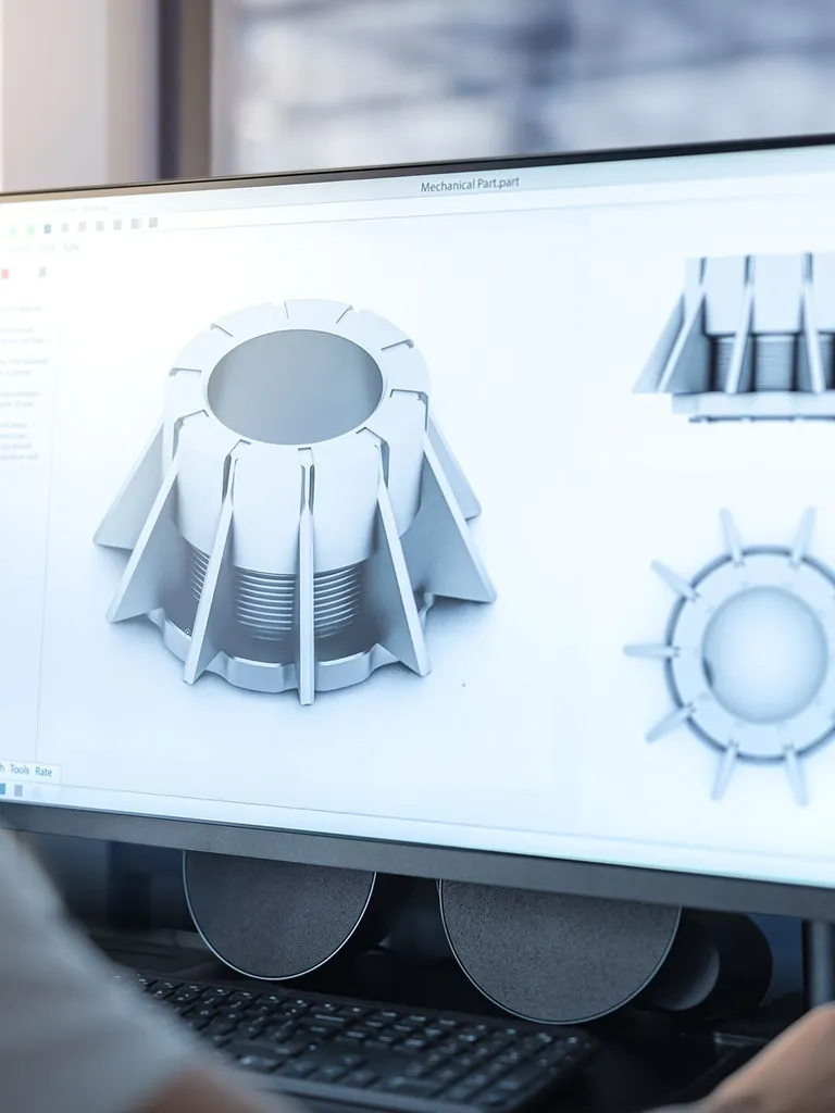 Man sitting by a desk designing a part on CAD-software