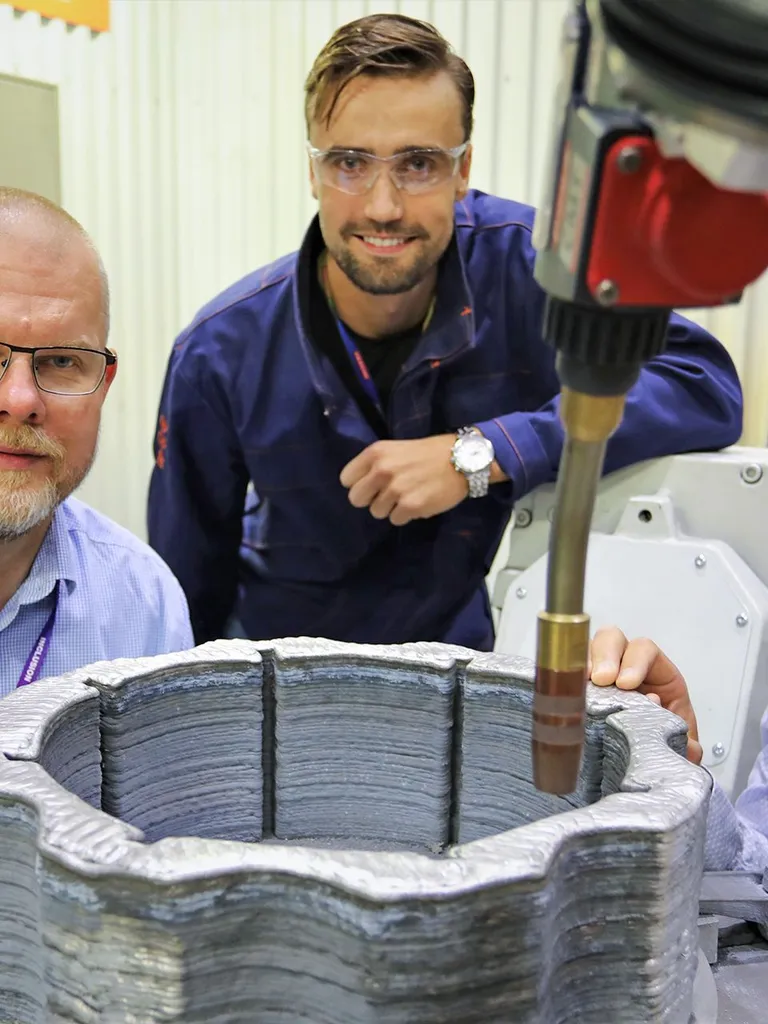 Technicians standing around metal 3d-printer
